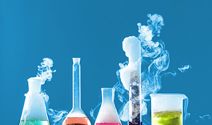 lab beakers and flasks filled with colourful liquid giving off fumes
