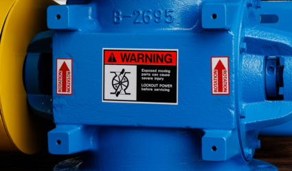 A blue ACS Valves rotary airlock valve with safety stickers